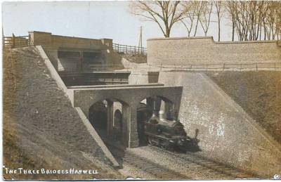 A steam locomotive passes beneath the canal and the road is above