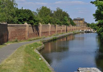 a large imposing brick wall beside the canal as it stretches ahead